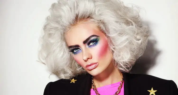 Portrait of young beautiful platinum blond woman with bold eyebrows and 80s style makeup