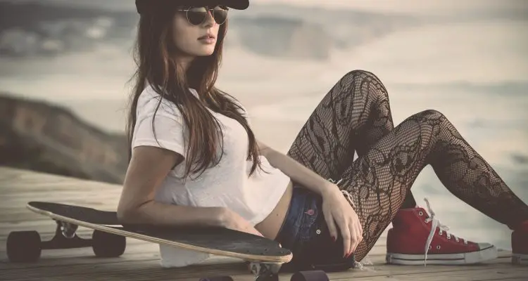 Beautiful and fashion young woman posing with a skateboard and converse's.