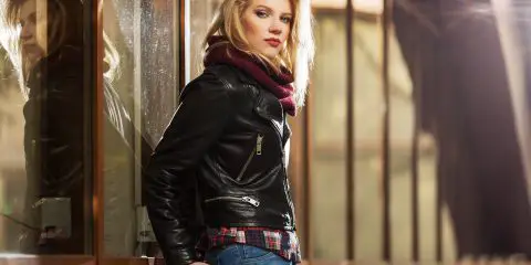 Young fashion blond woman in leather jacket at the mall window
