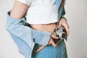 White crop top and short denim skirt with camera.