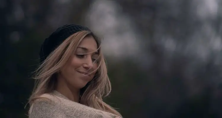 Women wearing a oversized sweater and hat smiling