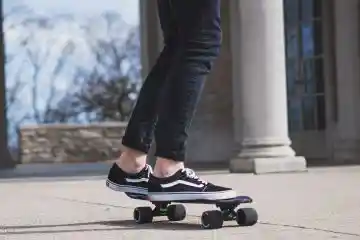 Man wearing skinny black jeans on skateboard