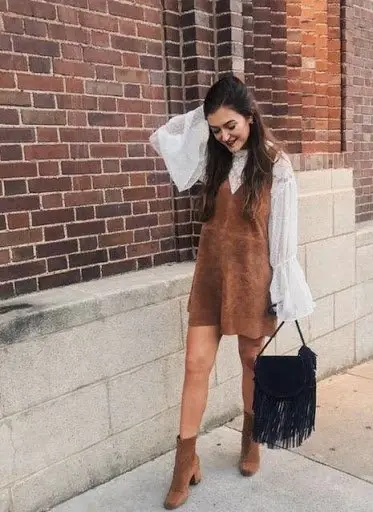 Women wearing brown pinafore dress with tan boots and beige top