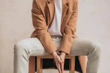 Man wearing eighties fashion clothing brown coat and white tee and jeans