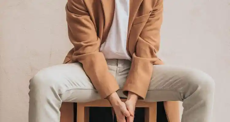 Man wearing eighties fashion clothing brown coat and white tee and jeans