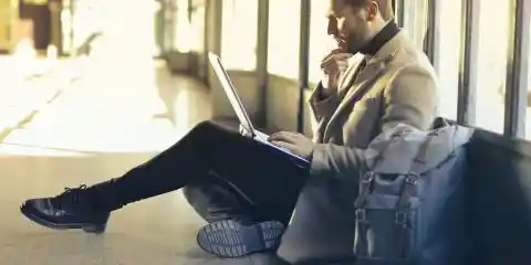 Man wearing a winter long coat in cream with laptop on his lap
