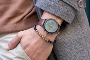 Man wearing a long winter coat with tan belt watch