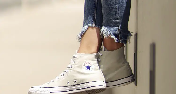 woman wearing white converse and ripped jeans
