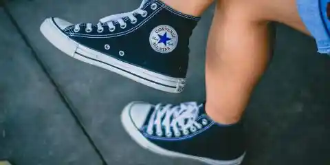 woman wearing black high top converse shoes with denim skirt