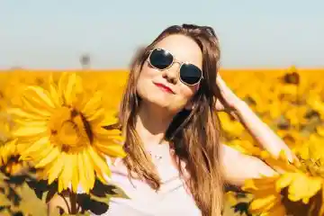 woman wearing sunglasses and denim jeans in a field of flowers