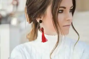 woman wearing statement earrings with white turtleneck