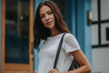 woman wearing white tee with blue denim shorts with black bag