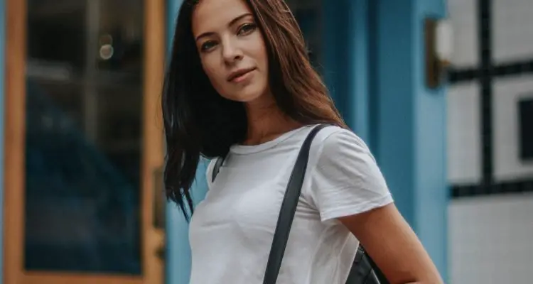 woman wearing white tee with blue denim shorts with black bag