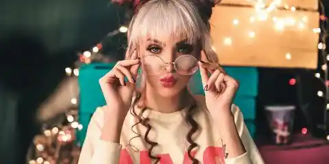 woman wearing 80s glasses and 80s style outfit with pink lipstick